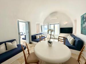 a living room with a white table and chairs at Ilia Oia in Oia