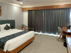 a bedroom with a bed and a desk and a window at The Blues Hotel in Chharodi