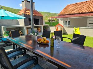 a wooden table with a bowl of fruit on a patio at Grey House with heated pool Kričke Drniš in Kričke