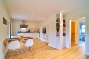 a kitchen with white cabinets and a wooden table and chairs at Oberhausen an der Nahe LIEBLINGSORT - Ferienappartements in Oberhausen +9 photos