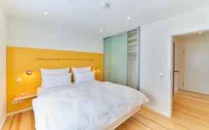 a bedroom with a white bed and a yellow wall at Oberhausen an der Nahe LIEBLINGSORT - Ferienappartements in Oberhausen