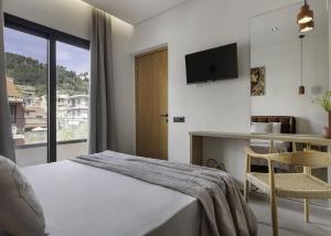 a bedroom with a bed and a desk and a television at D'Oliva, by ZanteWize in Zakynthos Town