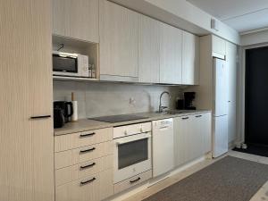 a kitchen with white cabinets and a microwave at Pramea Apartments Aallonharja 5 in Jyväskylä