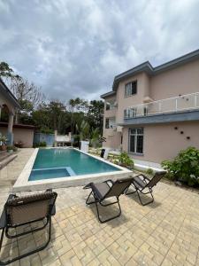 a swimming pool with two chairs and a house at La villa des anges in Kribi