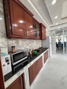 a kitchen with wooden cabinets and a microwave at La villa des anges in Kribi