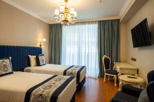 a hotel room with two beds and a chandelier at Panorama Lisi Grand Hotel in Tbilisi City