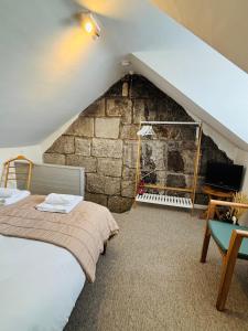 a attic bedroom with a bed and a stone wall at Foundry Cottage in Portland +33 photos