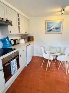 a kitchen with white cabinets and a table and chairs at Foundry Cottage in Portland