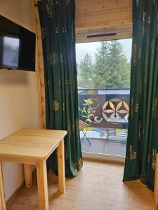 Habitación con mesa y vistas a un balcón. en Apartament Parzenica przy Termach Chochołowskich, en Witów
