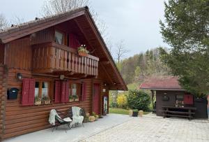 a wooden house with a balcony and a table at Počitniška hiša z dvema spalnicama Sauna & Jacuzzi in Gorica pri Slivnici