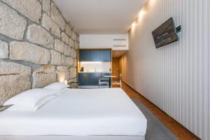 ポルトにあるGuestReady - Porto de Rio Residencesの白いベッドと石の壁が備わるベッドルーム1室