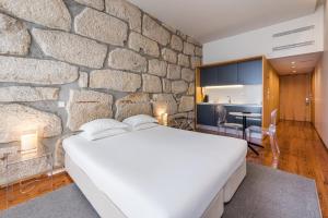 ポルトにあるGuestReady - Porto de Rio Residencesの石壁のベッドルーム1室、ベッド1台、デスクが備わります。 +44枚の写真