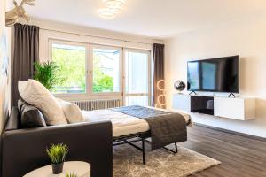 een woonkamer met een bed en een televisie bij Relax Apartment Black & White in Friedrichshafen