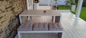 a wooden table with a bench with a cushion on a deck at Les Granges in Vigoulant