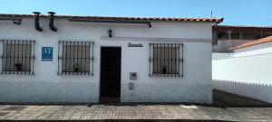 a white building with barred windows and a door at Bungalows Sierra San Benito in Cala