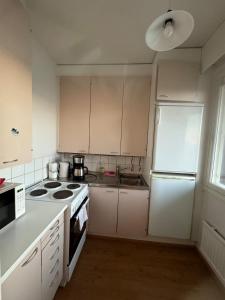 Una cocina con gabinetes blancos y un refrigerador blanco. en Kotimaailma-Studio Keskustassa, en Kokkola