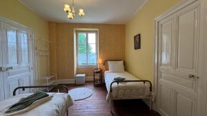 Un dormitorio con dos camas y una ventana. en Maison Belle Vie, en Saint-Symphorien-de-Marmagne