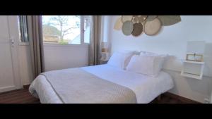 Un dormitorio con una cama blanca y una ventana. en VK Lake, en Aureilhan