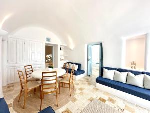 a living room with a blue couch and a table and chairs at Ilia Oia in Oia