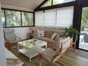 a living room with a couch and a table at Le Chalet d'Isabelle-sur la vélodyssée-drap-serviette in Sainte-Eulalie-en-Born