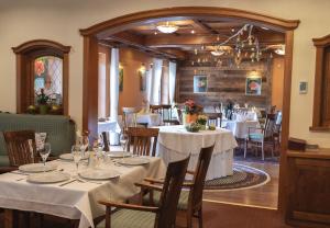 ein Esszimmer mit Tischen mit weißen Tischdecken in der Unterkunft Alpejski Boutique Hotel in Karpacz