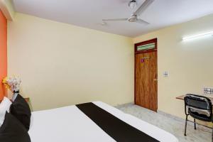 a bedroom with a bed and a desk and a door at Hotel O Balaji Palace in Noida
