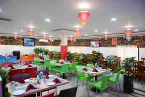 un restaurant avec des tables, des chaises vertes et des lumières dans l'établissement Barga Forest Inn, à Jāmb