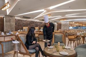 a chef standing next to a woman in a restaurant at Ramada Encore by Wyndham Ambala GT Road in Ambāla