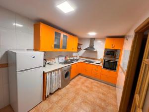 a kitchen with orange cabinets and a white refrigerator at Apartamento Turístico La Clase in La Zubia +5 photos