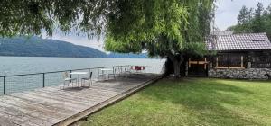 a wooden dock with tables and chairs next to a lake at Riviera 990 Chalet in (( Ogradena Nouă ))