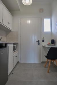 a kitchen with a white door and a table and a chair at Fiona Apartments Roda Corfu in Roda