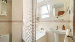 a bathroom with a shower curtain and a sink at APARTAMENTOS CARMEN in Maro