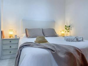 a white bedroom with a bed with a hat on it at APARTAMENTOS CARMEN in Maro