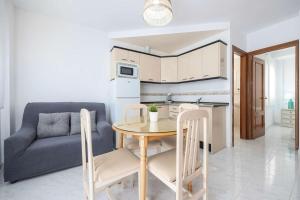a kitchen and dining room with a table and a couch at APARTAMENTOS CARMEN in Maro