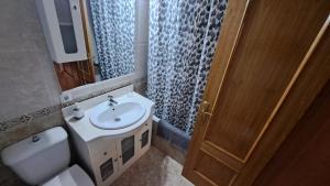 a bathroom with a sink and a toilet and a mirror at Apartamento Turístico La Clase in La Zubia