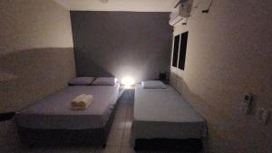 two beds in a room with a light on it at Apto 2 quartos Inteiro privativo Palmas TO in Palmas