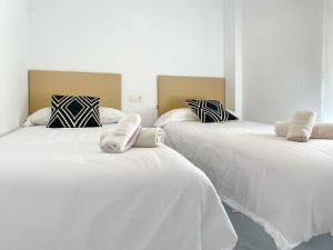two beds in a room with white sheets and pillows at APARTAMENTOS CARMEN in Maro