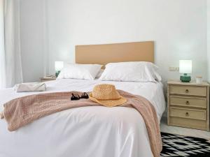 a bedroom with a bed with a hat and glasses on it at APARTAMENTOS CARMEN in Maro