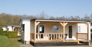 a tiny house with a porch and a deck at Camping Alkenhaer Appelscha Chalet 034 in Appelscha