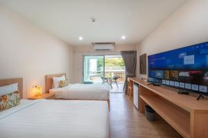 a hotel room with two beds and a flat screen tv at Ventus Phangan in Haad Rin