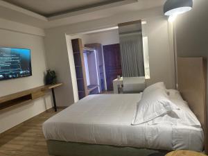 a bedroom with a white bed and a flat screen tv at Archontiko Liamas in Stavros