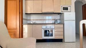 a kitchen with a white refrigerator and a microwave at APARTAMENTOS CARMEN in Maro