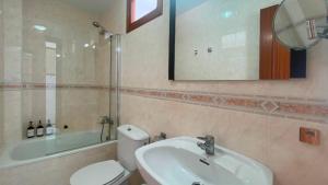 a bathroom with a sink and a toilet and a mirror at APARTAMENTOS CARMEN in Maro