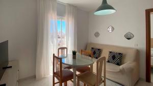 a dining room with a table and chairs and a couch at APARTAMENTOS CARMEN in Maro