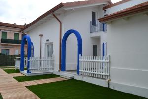 a white house with blue doors and green grass at B&B Residenza Marina in Marina di Carrara