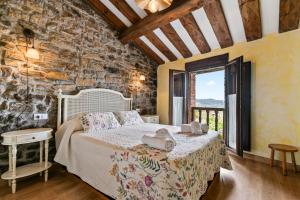 a bedroom with a bed and a stone wall at Casa Rural Adrimar in Selorio