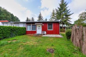 a red shed with a white door in a yard at Korswandt, Ostseebungalow in Korswandt