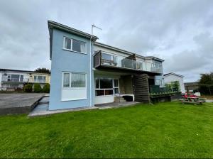 a blue house with a lawn in front of it at Sunvalley hideaway in Pembrokeshire