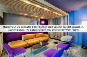 ein Wohnzimmer mit einem Sofa und lila Stühlen in der Unterkunft B&B Hotel Essen-Hbf in Essen