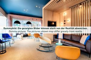 eine Lobby mit einem Sofa und Stühlen in einem Zimmer in der Unterkunft B&B Hotel Essen-Hbf in Essen